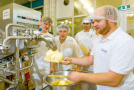 Mehrere Schüler stellen Butter mir einer großen Butterungsmaschine her